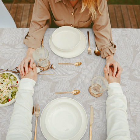 Nordfavn Edna – Textilvaxduk med diskret bladmönster på sandfärgad bakgrund, bord