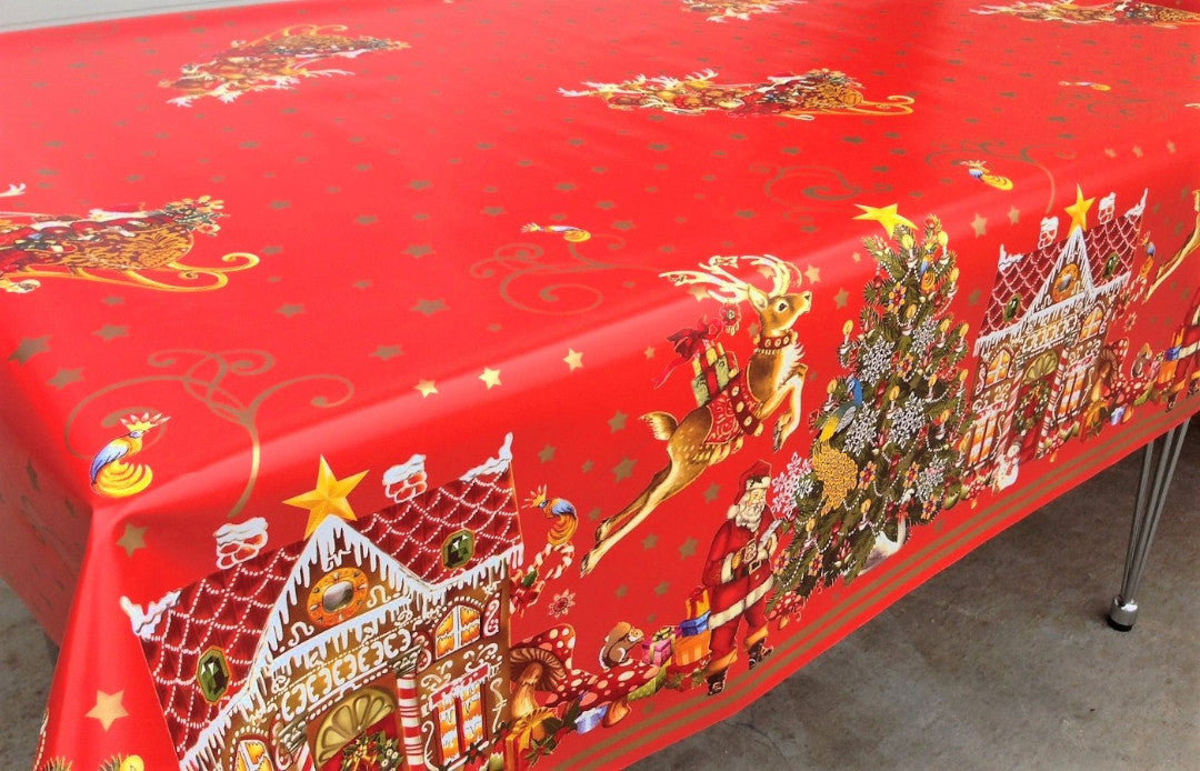 Jul i Kagehuset vaxduk på matbord med julmotiv som granar och pepparkakshus