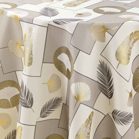 Närbild av det vackra bladmotivet med gulddetaljer på Natane Natural rund duk